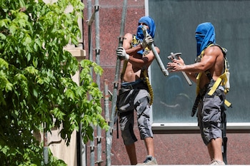 Trabajadores en un andamio se protegen la cabeza en Bilbao, a 22 de junio de 2026. (EFE/Luis Tejido)