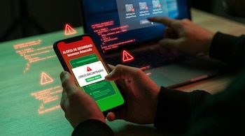 Una persona sostiene un smartphone con una alerta de virus, mientras una mano elimina aplicaciones sospechosas en un portátil con código digital y símbolos de advertencia.
