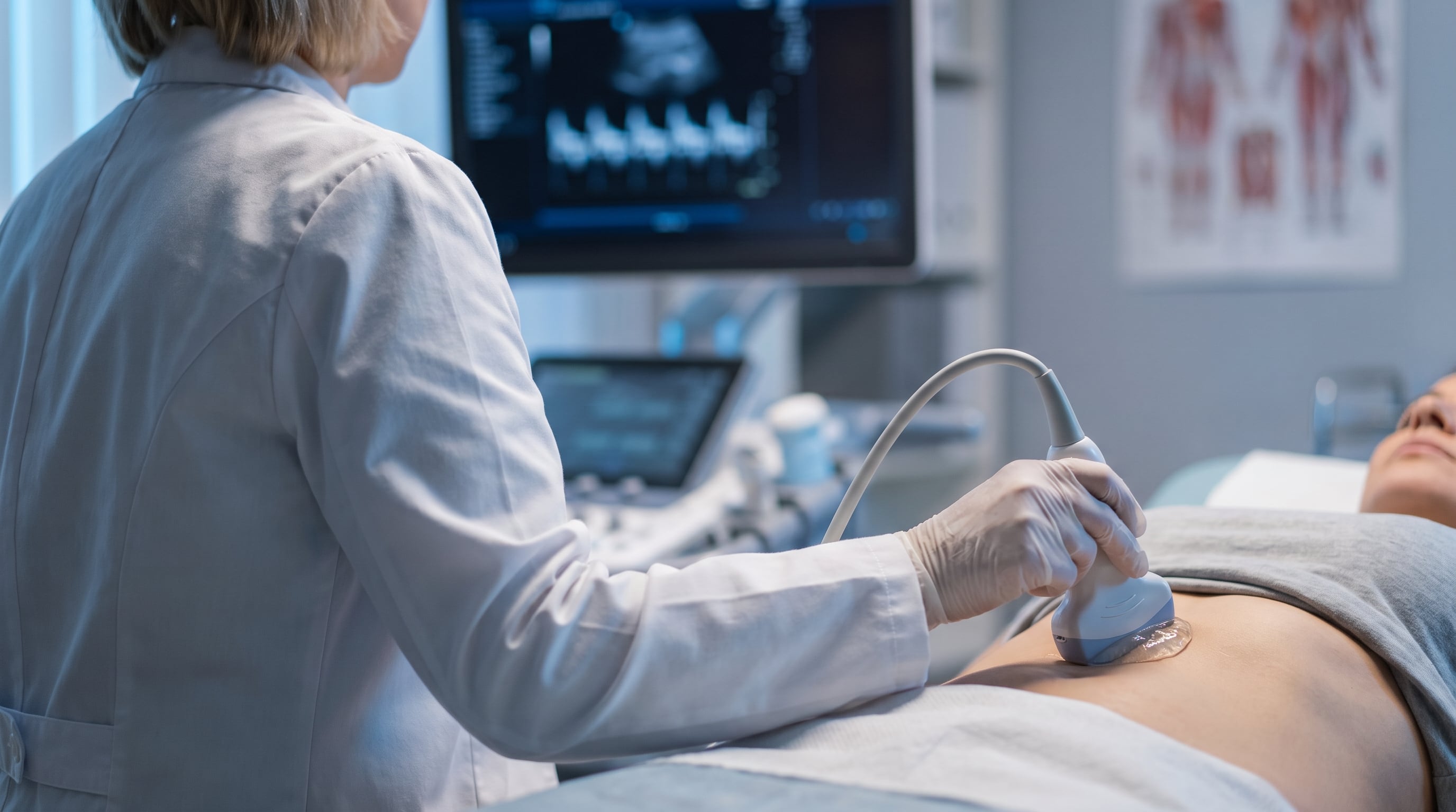 Un médico realiza una ecografía abdominal a un paciente recostado en una camilla para evaluar el sistema hepatobiliar. (Imagen Ilustrativa Infobae)