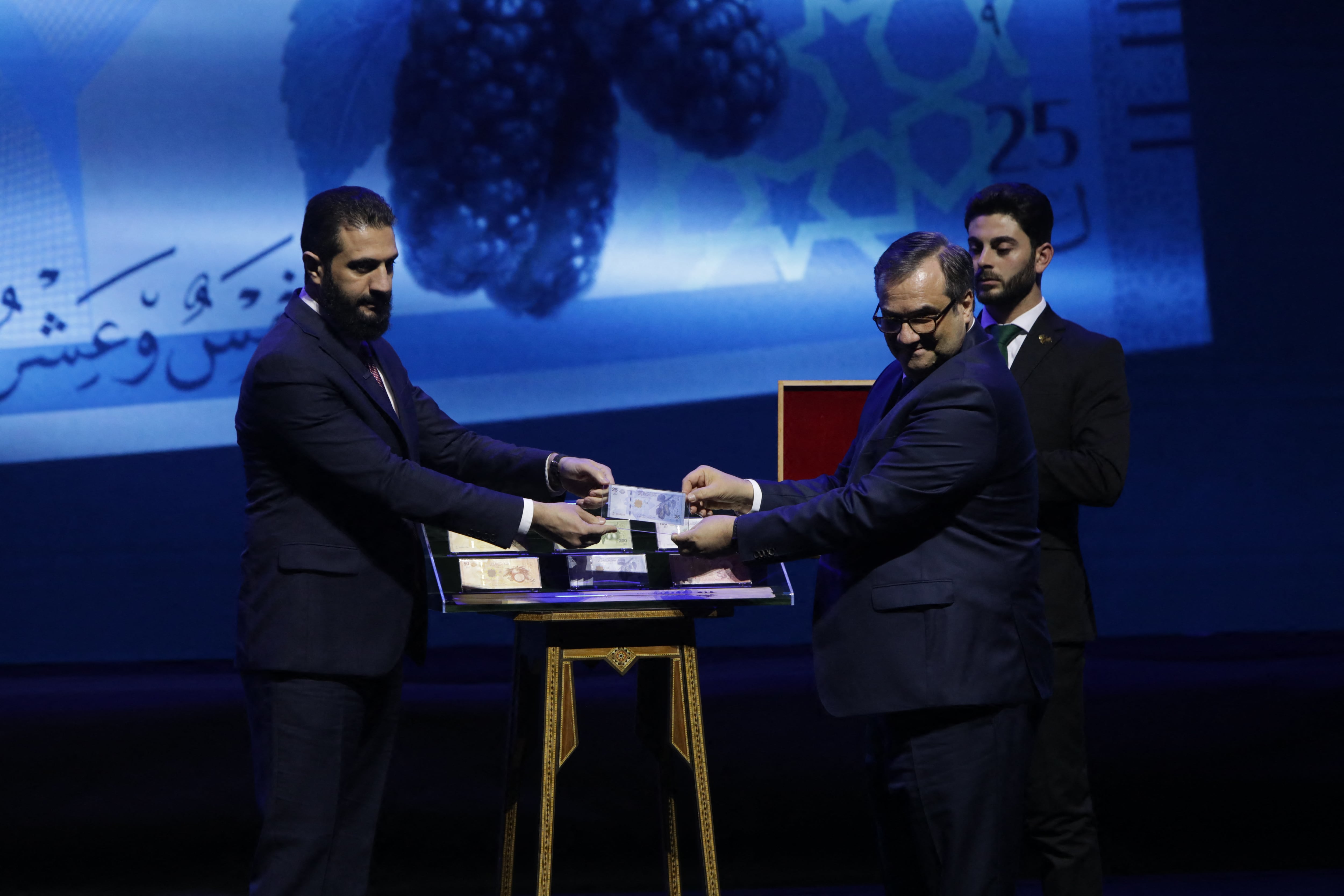 Durante una ceremonia en el Palacio de Conferencias de Damasco, Al Sharaa presentó los nuevos billetes junto al gobernador del Banco Central, Abdelkader Husrieh, y destacó el carácter simbólico del rediseño (Bakr ALKASEM / AFP)