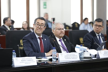 Autoridades y asistentes sentados alrededor de una mesa curva con micrófonos frente al emblema del Congreso de la República de Guatemala