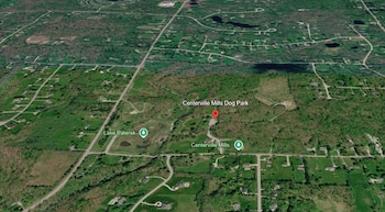 Vista de mapa satelital con áreas verdes y carreteras, marcada con un pin rojo con el texto Centerville Mills Dog Park