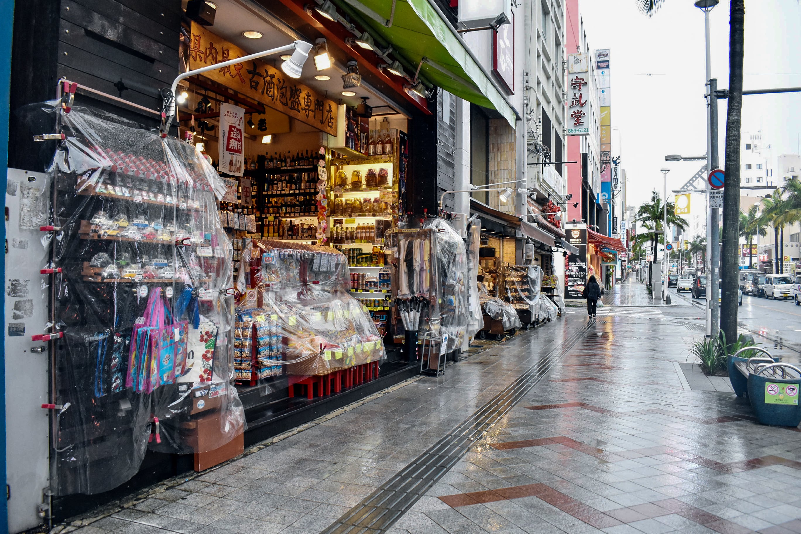Las tiendas cubren su mercancía con plástico para protegerla de la lluvia al paso del tifón Saudel por Naha, el 26 de agosto de 2026 (Hiroaki YAMASHIRO / AFP)