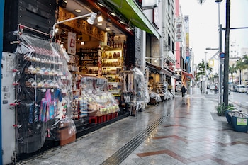 Las tiendas cubren su mercancía con plástico para protegerla de la lluvia al paso del tifón Saudel por Naha, el 26 de agosto de 2026 (Hiroaki YAMASHIRO / AFP)