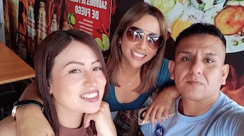 Dos mujeres y un hombre sonríen a la cámara mientras posan juntos en el interior de un restaurante