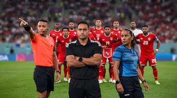 Tres árbitros y diez jugadores de fútbol con uniforme rojo en un estadio; uno de los jugadores sujeta una bandera de Panamá.