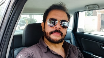 Un hombre con barba y gafas de sol sentado en el interior de un vehículo.