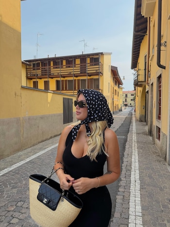 Wanda Nara con lentes de sol, pañuelo a lunares en la cabeza y un bolso beige y negro en una calle empedrada