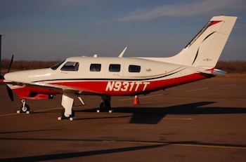 Una avioneta de color blanco y rojo con la matrícula N931TT se encuentra estacionada en una pista de asfalto