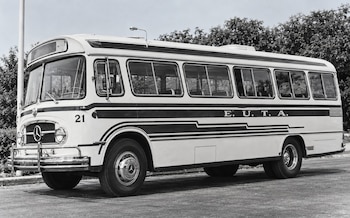 Autobús en blanco y negro con el emblema de Mercedes-Benz y la inscripción E.U.T.A., estacionado en una superficie pavimentada frente a árboles