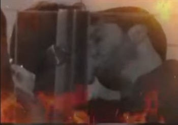 Imagen oscura y borrosa que muestra a Mayra Goñi y Rodrigo Brand besándose, con un efecto de llamas en primer plano