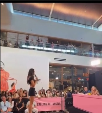 Natalie Vértiz en el escenario con micrófono, vistiendo top oscuro y shorts, frente a un panel de jueces y público en un evento