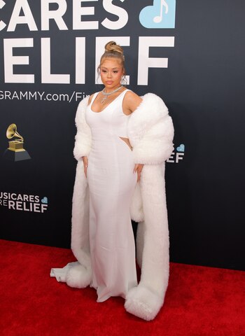 La cantante Latto en los Grammys: un vestido blanco de corte ajustado y escote pronunciado, que destacó por su elegancia minimalista. Complementó el look con un abrigo largo de piel sintética en tono blanco