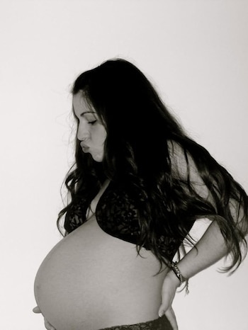 Fotografía en blanco y negro de Gianinna Maradona de perfil, mostrando su vientre de embarazada, con el pelo largo y oscuro, luciendo lencería de encaje