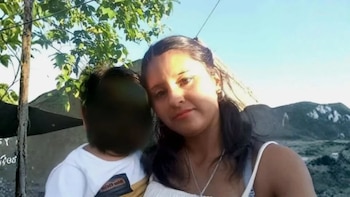 Una joven con bufanda de tonos fucsia y negro mira a la cámara en un primer plano
