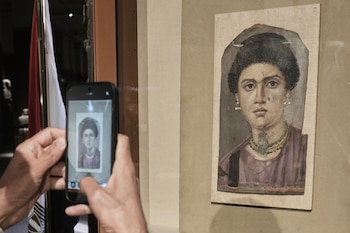 Unas manos sostienen un teléfono inteligente para fotografiar el retrato antiguo de una mujer sobre un panel
