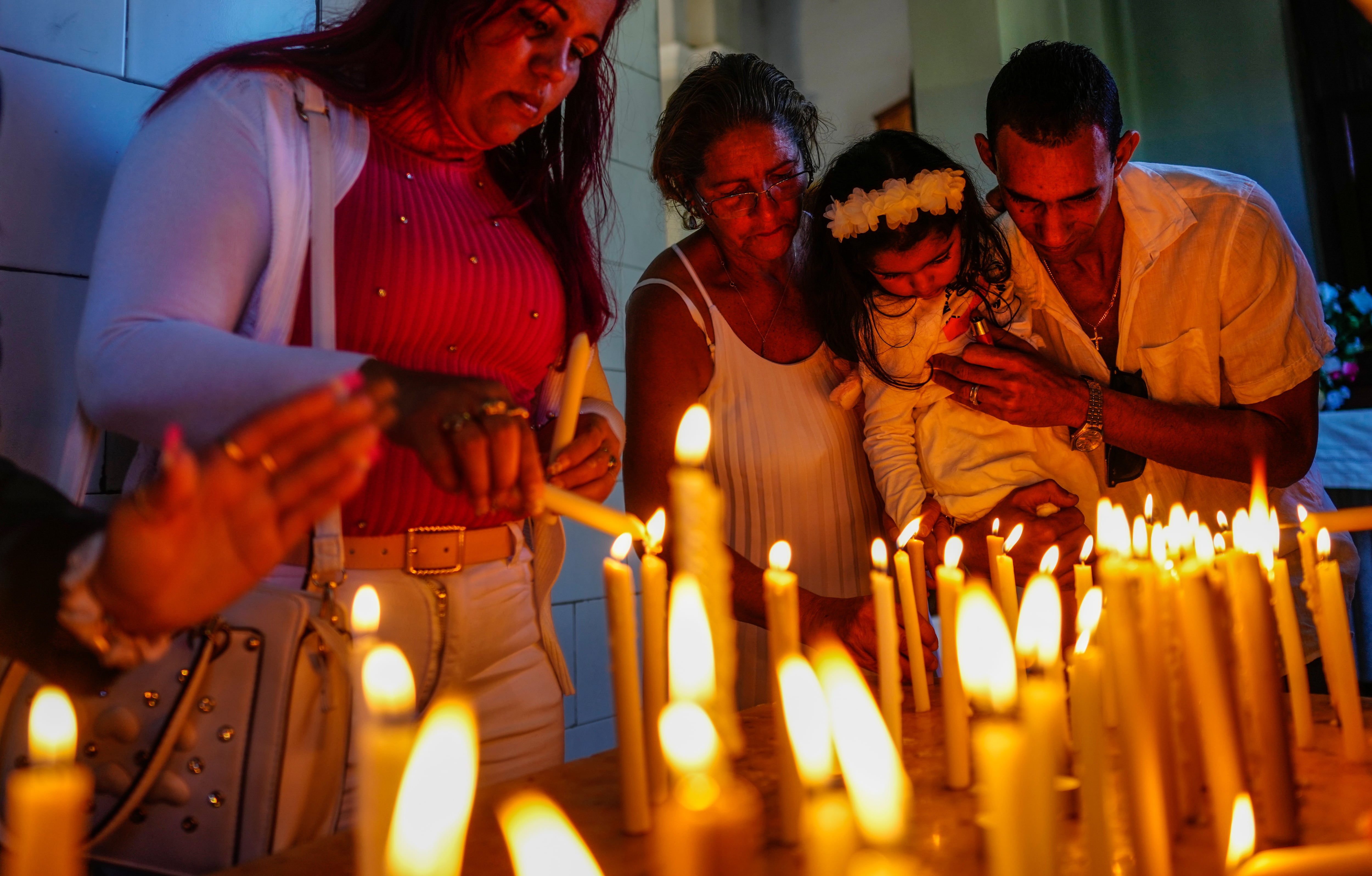 ARCHIVO - Varias personas encienden velas en honor de la santa patrona de Cuba, la Virgen de la Caridad del Cobre, el 11 de febrero de 2024, en su santuario en El Cobre, Cuba. La Virgen reconocida por el Vaticano, venerada por los católicos y por seguidores de las tradiciones afrocubanas de la santería, se encuentra en el corazón de la identidad cubana. (AP Foto/Ramón Espinosa, archivo)