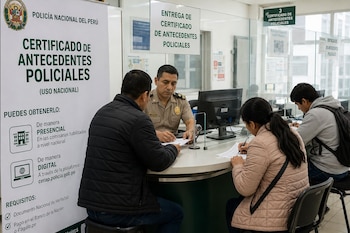 Un policía en una ventanilla de atención atiende a personas sentadas al otro lado del cristal frente a un cartel informativo