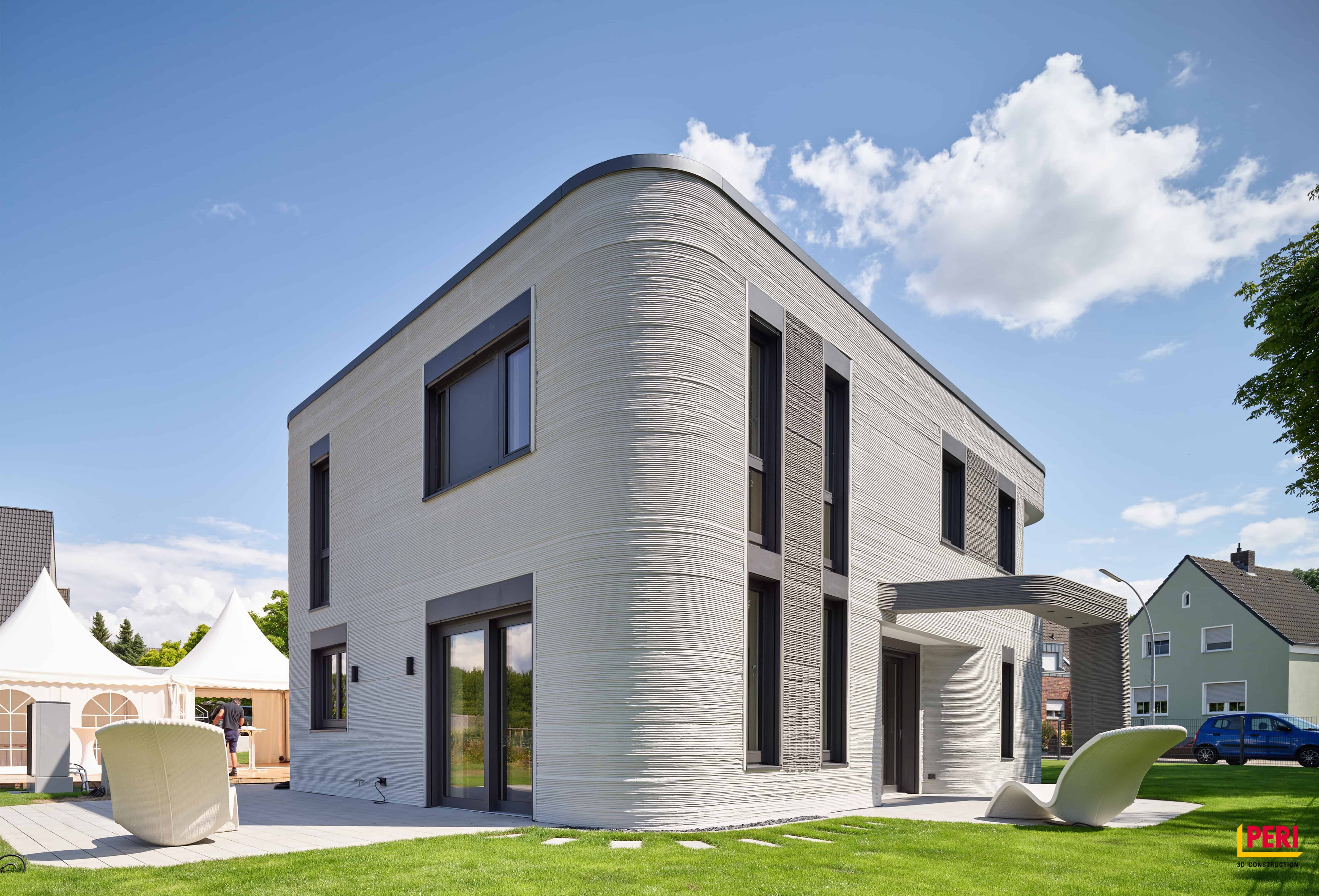 Una casa residencial de dos pisos, con una fachada de capas horizontales, representa una vivienda construida con tecnología de impresión 3D. (COBOD)