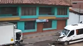 Un furgón blanco y una miniván blanca con la parte delantera destruida permanecen detenidos frente a un inmueble de dos pisos