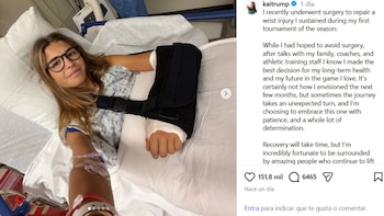 Una mujer con gafas y bata médica reposa en una cama de hospital con el brazo sujeto en un cabestrillo y una vía en la mano
