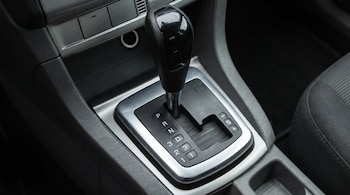 Vista superior de una palanca de cambios de coche automático con letras P, R, N, D y números 3, 2, 1. La base es plateada y el pomo negro.