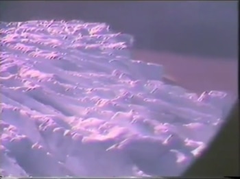 Superficie blanca texturizada con ondas y reflejos púrpuras. Un área oscura aparece en el lateral derecho de la imagen