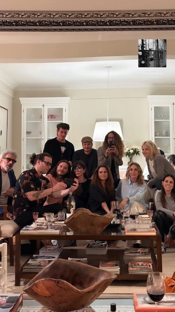 Un grupo de diez personas posa reunido alrededor de una mesa de centro con copas de vino y libros