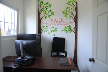 Una oficina con un escritorio, silla de oficina, monitor de computadora, archivador y un mural de árboles con un mensaje inspirador en la pared