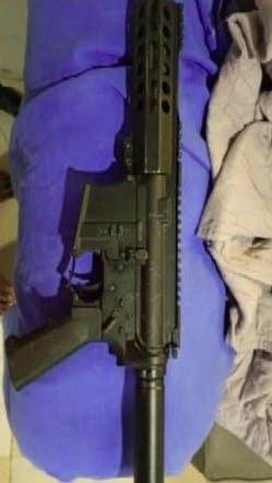 Un fusil de color negro permanece sobre una superficie de tela azul en el marco de la investigación referida a Pablo Bebote Álvarez.
