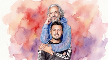 Pintura de acuarela de dos hombres. Uno con cabello gris y saco azul abraza al otro hombre con cabello oscuro. El fondo es un lavado de colores rojo, naranja y morado.