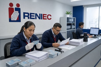 Tres trabajadores sentados tras un mostrador con el logotipo de Reniec revisan papeles impresos y tarjetas de identidad.