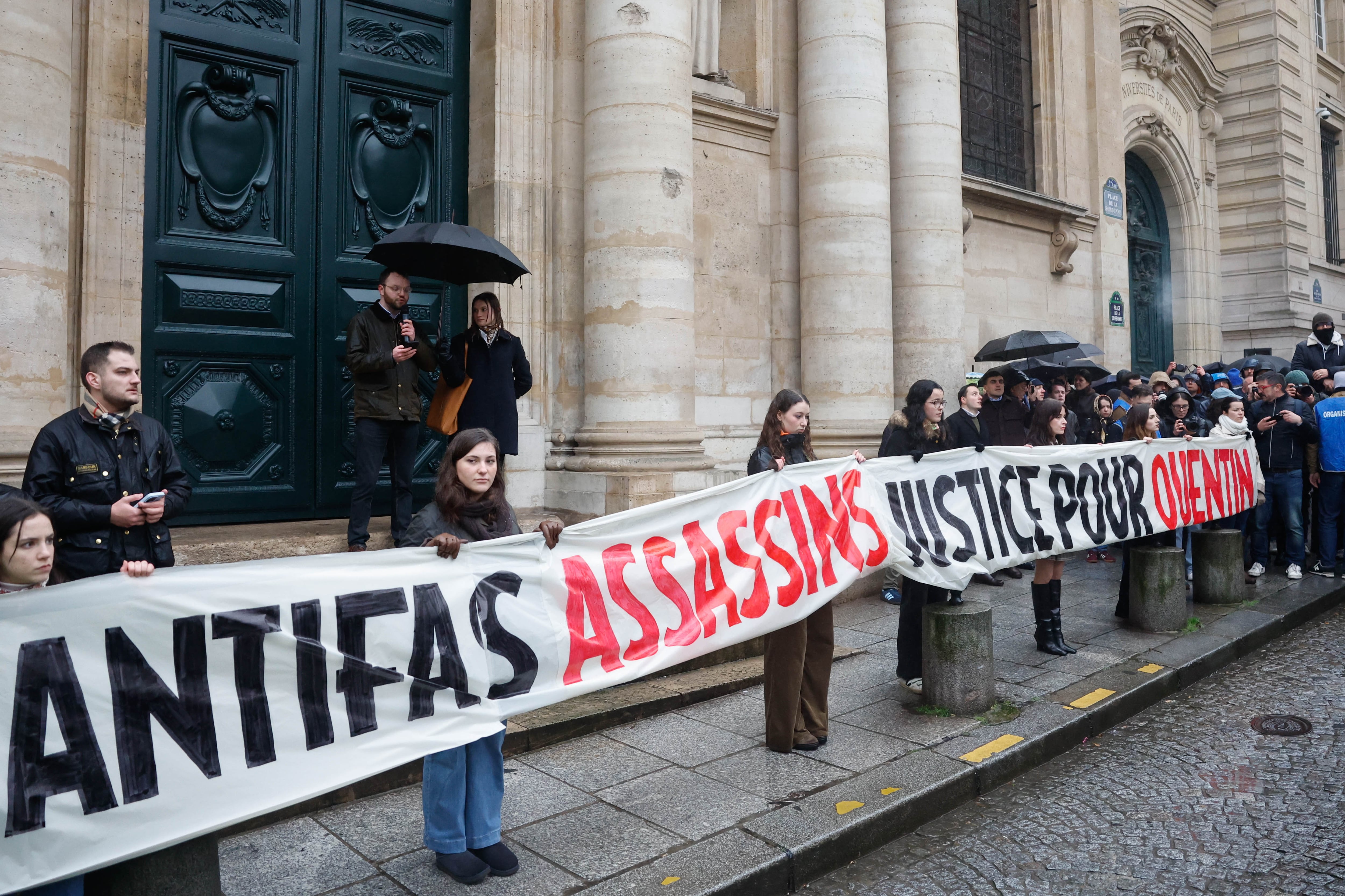 Personas sosteniendo un cartel que dice 'Asesinos de Antifa, justicia para Quentin', mientras se reúnen para rendir homenaje a Quentin, el estudiante de 23 años asesinado en Lyon, en la place de la Sorbonne, París, Francia, 15 de febrero de 2026. EFE/EPA/MOHAMMED BADRA
