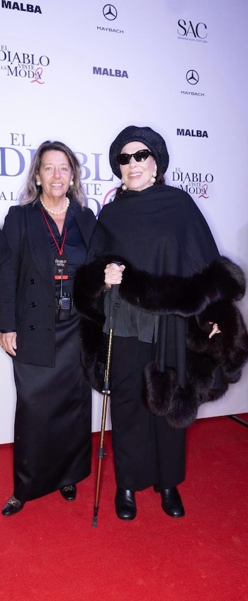 Graciela Borges, con boina y gafas de sol, posa junto a María Claudia Pedrayes en una alfombra roja. Ambas visten de negro frente a un fondo blanco con logos