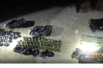 Granadas verdes, tubos lanzadores, armas de fuego y marcadores numéricos de peritaje yacen sobre la tierra