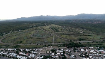 Vista aérea del Autódromo General San Martín de Mendoza con pistas sinuosas en un terreno verde, un barrio residencial en primer plano y montañas al fondo