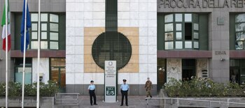 Fachada de un edificio con la inscripción de la Procura della Repubblica, dos agentes uniformados y un militar frente a la entrada