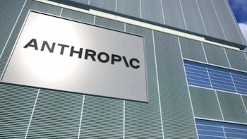 Logotipo de "ANTHROPIC" en letras negras sobre fondo blanco, en la fachada gris de un edificio moderno con diseño de celosía y ventanas azules
