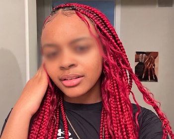 Una joven con trenzas largas de color rojo y camiseta negra, con el rostro difuminado