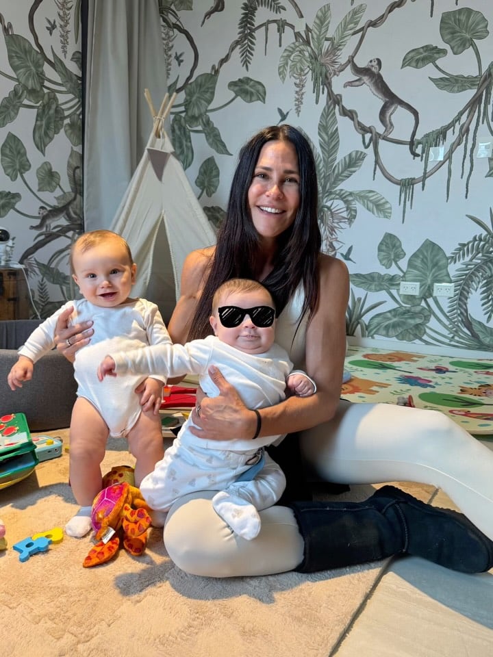 Carolina Baldini sonríe feliz mientras comparte un tierno momento con sus nietos Faustino y Tullio en un ambiente hogareño y lúdico