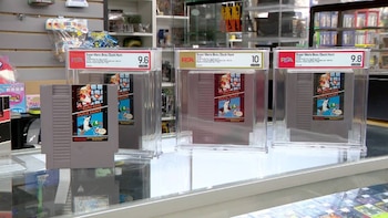 Cuatro cartuchos de videojuego Super Mario Bros./Duck Hunt, tres dentro de estuches protectores con etiquetas PSA que indican calificaciones de 9.6, 10 y 9.8