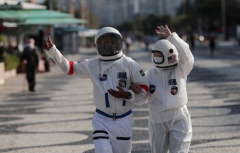 El contador brasileño Tercio Galdino (c), de 66 años, y su esposa, Alicea Galdino (d), fueron registrados este viernes al caminar por la playa de Leme con trajes protectores para evitar la contaminación con Coronavírus, en Río de Janeiro (Brasil). EFE/Antonio Lacerda