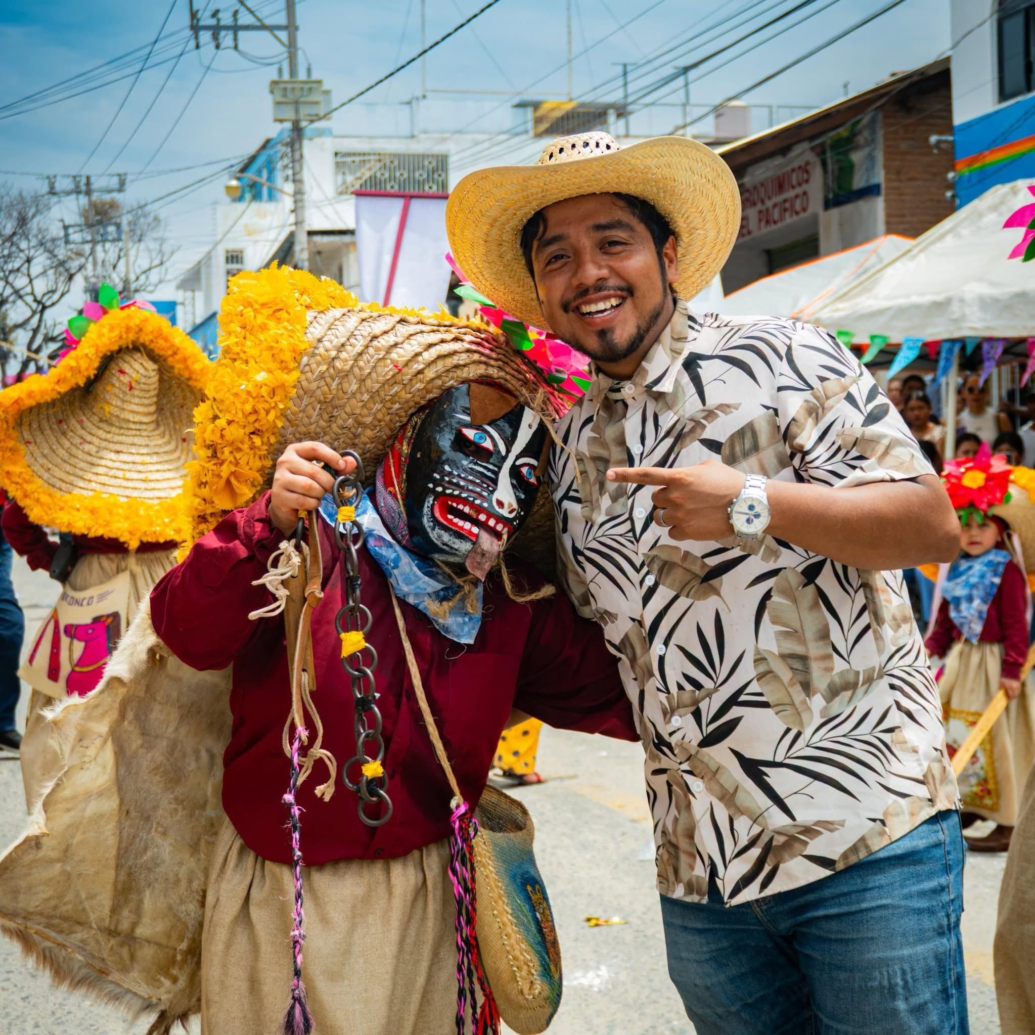 El creador digital Emerson Navarrete posa junto a un participante caracterizado con vestimenta tradicional y máscara durante un desfile festivo. (Facebook)