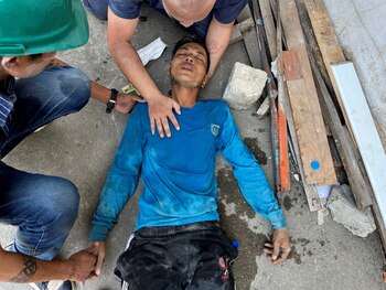 A casualty lies on the gound as people assist him after the tremors of a strong earthquake that struck central Myanmar on Friday affected Bangkok, Thailand, March 28, 2025. REUTERS/Ann Wang
