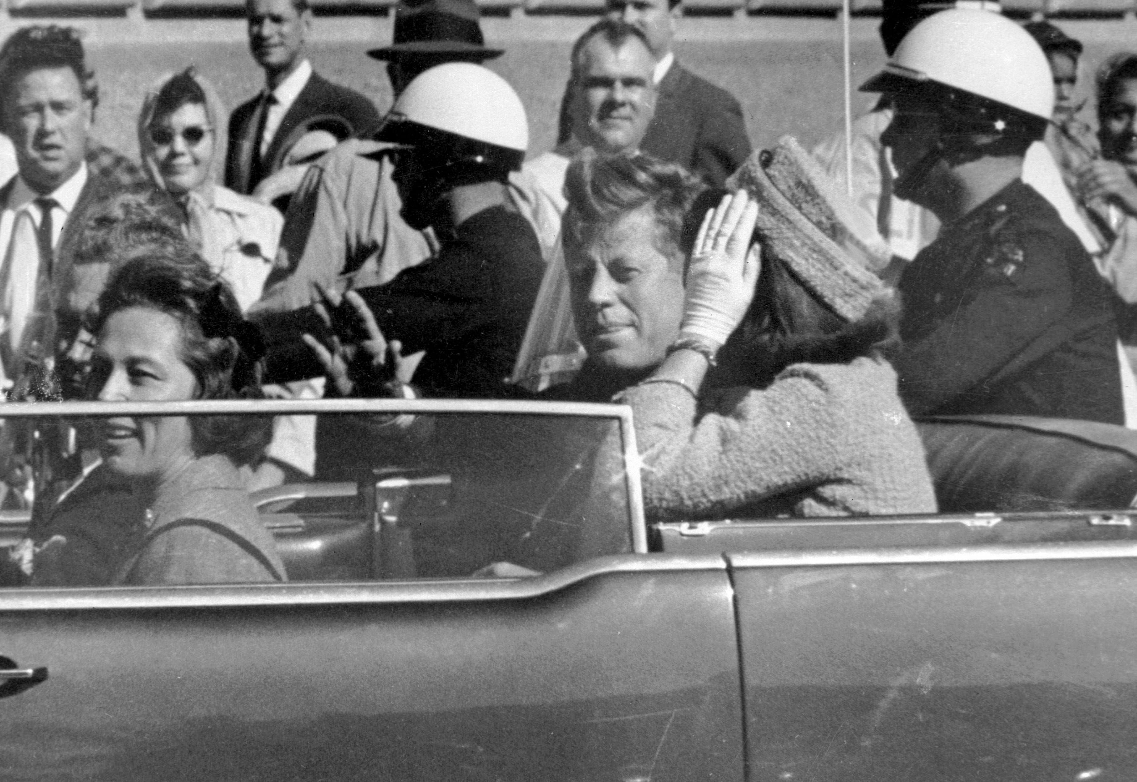 ARCHIVO - En esta fotografía de archivo del 22 de noviembre de 1963, el entonces presidente John F. Kennedy saludaba desde su automóvil durante una caravana en Dallas. Junto a Kennedy viajan la primera dama Jacqueline Kennedy (a la derecha), Nellie Connally (segunda por la izquierda) y su esposo, el gobernador de Texas John Connally (en el extremo izquierdo) (Foto AP/Jim Altgens, Archivo)