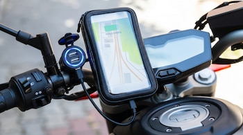 Manillar de motocicleta, teléfono móvil en soporte, pantalla con mapa y ochenta y cinco por ciento de carga, puerto USB doble iluminado, cable, depósito.