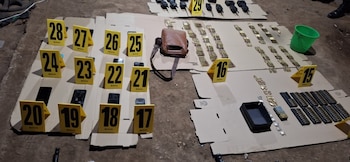 Objetos incautados en el suelo: municiones, radios, teléfonos inteligentes, una bolsa de cuero y marcadores de evidencia numerados