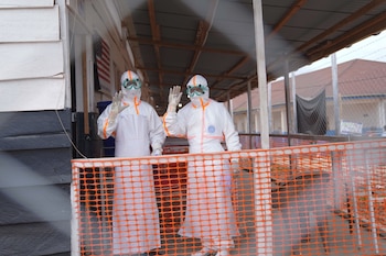 Trabajadores de salud con equipo de protección saludan dentro de un centro de tratamiento contra el ébola en Bunia, en la provincia de Ituri, epicentro del brote que ya superó los 2.000 muertos (AP Foto/Dieudonne Dirole)