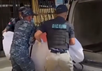 Efectivos de la Policía Nacional y de la DICRIM trasladan uno de los cuerpos hallados en el apartamento del Distrito Nacional, mientras continúa la investigación del caso (Cortesía: Lo que pasa RD).