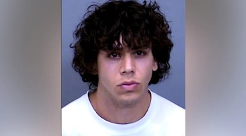 Fotografía policial de Heston James, un joven de cabello rizado oscuro y camiseta blanca sobre un fondo gris